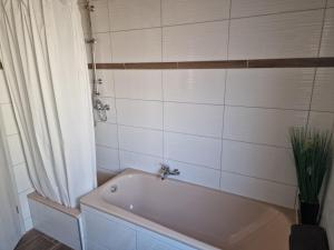 a white tub in a bathroom with a curtain at Berger´s Apartment-Hotel in Grafenwöhr