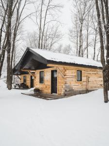 uma cabana de madeira na neve na floresta em Chalet - Abenaki Aventure em Pierreville