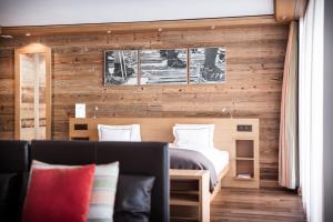 - une chambre avec des murs en bois, un lit et un canapé dans l'établissement Petit Chalet by Schönegg, à Zermatt