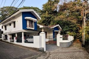 a blue and white house with a fence at Mylankal House in Kottayam