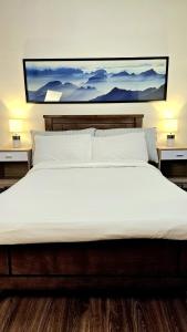 ein großes weißes Bett mit einem Gemälde an der Wand in der Unterkunft Guest Favorite House in Biñan in Biñan