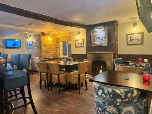 een restaurant met tafels en stoelen en een open haard bij Crown Hotel Cotswold in Blockley