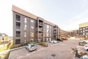 een appartementencomplex met auto's geparkeerd op een parkeerplaats bij Luxury Modern 2 Bed Apartment in Ebbsfleet - 20mins from London in Swanscombe