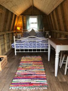 a bed in a room with a table and a rug at Penhallow House Glamping Retreat in Newlyn East