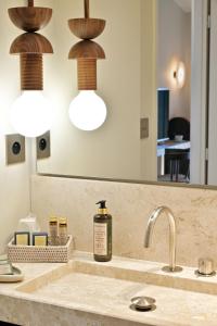 een wastafel in de badkamer met een fles zeep en een spiegel bij Hôtel Abbartello in Olmeto
