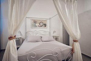 a bedroom with a white canopy bed with curtains at A ca' de Lisetta in Albenga