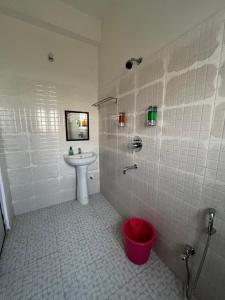 uma casa de banho em azulejos brancos com um lavatório e um WC. em USC Home Stay-304 em Guwahati