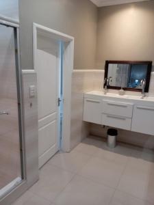 a bathroom with a sink and a mirror and a shower at KWR B&B in Witbank