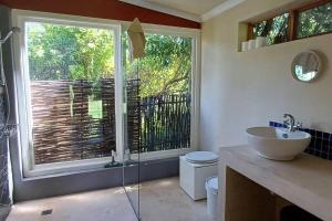 a bathroom with a toilet and a sink and a window at River Studio in Barrydale