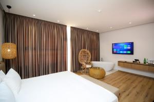 ein Schlafzimmer mit einem Bett, einer Badewanne und einem TV in der Unterkunft Oricon Coast Luxury Resort in Orikum