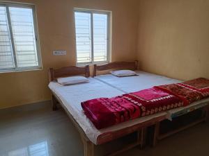 a large bed in a room with two windows at RAJ MAHAL GUEST HOUSE in Shānti Niketan