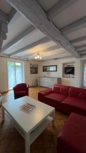 uma sala de estar com um sofá vermelho e uma mesa em Location appartement dans Maison Basque em Urcuit
