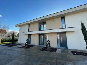 biały budynek z drzewami przed nim w obiekcie Luxury Apartments in Balatonalmádi, Almádi Lux Apartman II - Crystal White w mieście Balatonalmádi