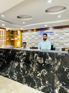two men standing behind a counter in a restaurant at Hotel Chetan International in Bangalore