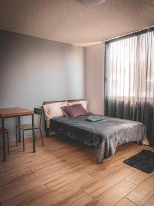 Schlafzimmer mit einem Bett, einem Tisch und einem Fenster in der Unterkunft Urban Style Retreat, Rooftop Views, CDMX 4 in Mexiko-Stadt
