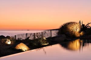 una piscina con puesta de sol en el fondo en Hôtel Abbartello, en Olmeto