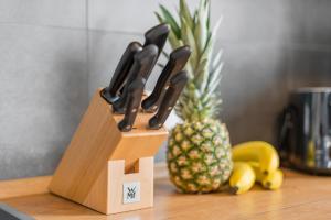 einem Holzblock mit Messern neben einer Ananas in der Unterkunft SEEzeit Maisonette in direkter Seenähe in Friedrichshafen
