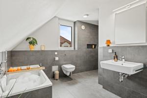 ein Badezimmer mit einem Waschbecken, einem WC und einer Badewanne in der Unterkunft SEEzeit Maisonette in direkter Seenähe in Friedrichshafen