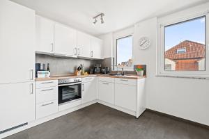 eine Küche mit weißen Schränken und einem Fenster in der Unterkunft SEEzeit Maisonette in direkter Seenähe in Friedrichshafen