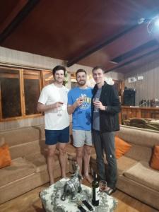 tres hombres parados en una sala de estar con copas de vino en EL TRAPICHE, en Sigchos