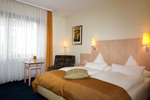 um quarto de hotel com uma cama grande e uma cadeira em Hotel Deutsches Haus em Lampertheim