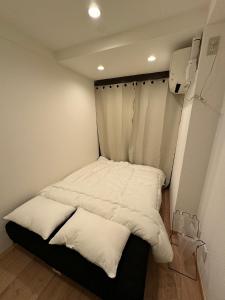 a bed in a small room with white sheets at waseda house in Tokyo