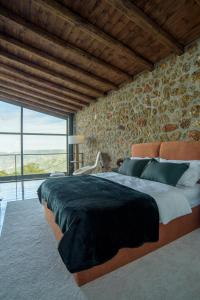 een slaapkamer met een groot bed en een groot raam bij Heartbeat Mountain Escapes in Kato Trikala Korinthias