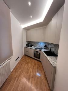 a kitchen with white cabinets and a wooden floor at Apartment Aurora Rho Fiera in Milan