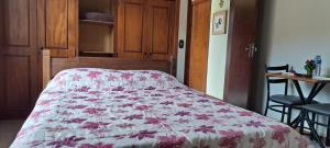 a bedroom with a bed with a floral bedspread at Suíte Com Estacionamento Perto do Centro in Campos do Jordão +2 photos