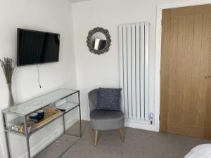 um quarto com uma cadeira, uma televisão e uma mesa em Porthkidney Suite, Carbis Bay, St Ives, free parking, near beach em Carbis Bay