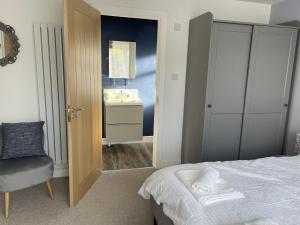 1 dormitorio con cama, silla y espejo en Porthkidney Suite, Carbis Bay, St Ives, free parking, near beach, en Carbis Bay