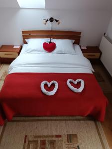 two hearts on a bed with a red blanket at Pasager House in Sovata