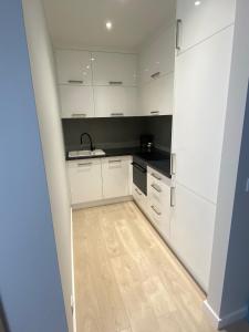 a kitchen with white cabinets and a wooden floor at Apartament Atrium in Gdynia