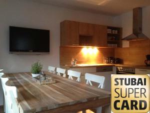a kitchen with a wooden table and white chairs at Ferienwohnung Dorfpub in Neustift im Stubaital