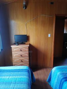 a bedroom with two beds and a television on a dresser at Hospedaje Familiar Doña Juanita in Puerto Montt