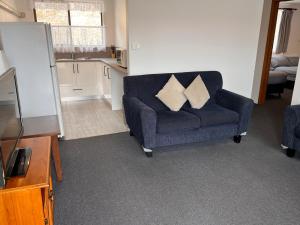 uma sala de estar com um sofá azul com duas almofadas em Regatta Point Tavern & Holiday Villas em Strahan