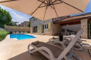 a patio with an umbrella and chairs and a pool at Villa Ema in Tar