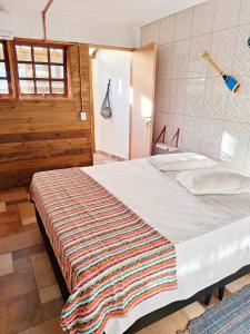 a bedroom with a large bed with a blanket on it at Suítes Praia Barequeçaba in São Sebastião