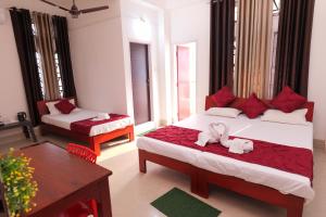 um quarto com 2 camas e almofadas vermelhas em USC Home Stay-307 em Guwahati