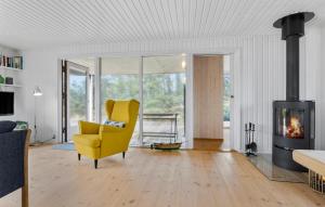 a living room with a yellow chair and a fireplace at Pet Friendly Home In Brovst With Kitchen in Brovst