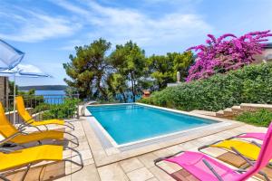 - une piscine avec deux chaises et une paire dans l'établissement Villa Penava, private beach, pool and 7min to Trogir, à Trogir