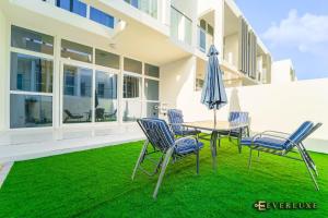 een patio met een tafel en stoelen en een parasol bij Everluxe Smart 2 Bedroom Villa In Akoya in Dubai