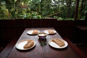 una mesa de madera con cuatro platos de comida. en Jungle Woods 900kandi, en Wayanad