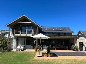 una casa con un paraguas delante en Lakeside home in security estate with solar power en Ciudad del Cabo