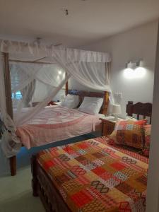 a bedroom with two beds and a canopy bed at Harbour key cottages in Malindi