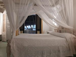 a bedroom with a white bed with a canopy at Harbour key cottages in Malindi
