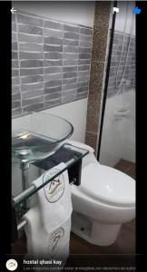 La salle de bains est pourvue de toilettes et d'une table en verre. dans l'établissement Hostal Qhasi Kay, à Huancayo