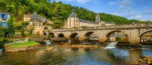 a bridge with ducks in the water in front of a building at Studio cosy, neuf, hyper centre in Brantôme