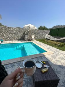 uma pessoa segurando uma xícara de café ao lado de uma piscina em Villa Doğa 2 em Fethiye