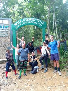 un grupo de personas de pie delante de un cartel en Jungle treking & Jungle Tour booking with us, en Bukit Lawang